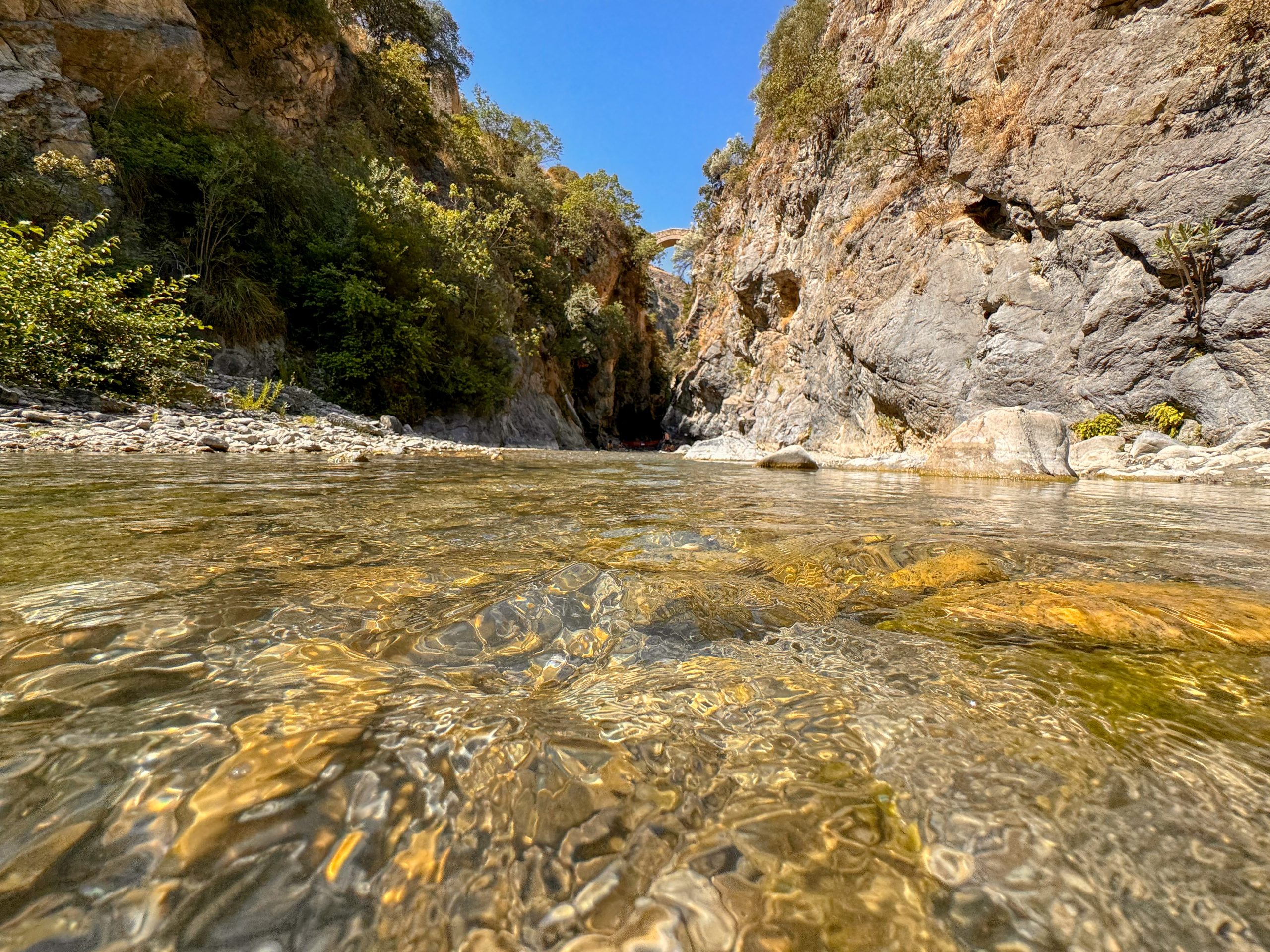 Le acque del torrente raganello all'interno delle sue gole con il ponte del diavolo sullo sfondo